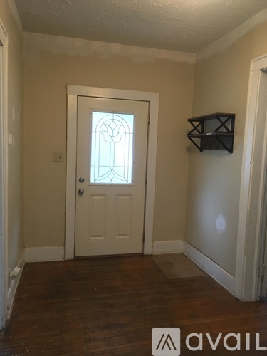 A white door with a stained glass window is in a room with wooden floors.
