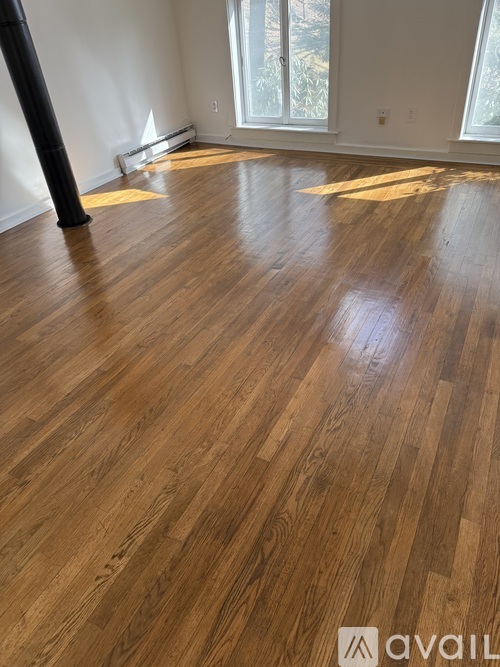 A room with wooden flooring and a large window.