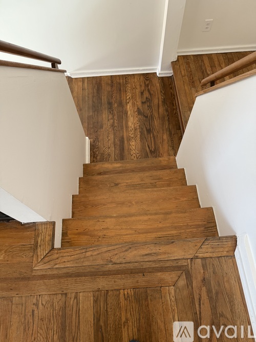 A wooden staircase with a white wall on the side.