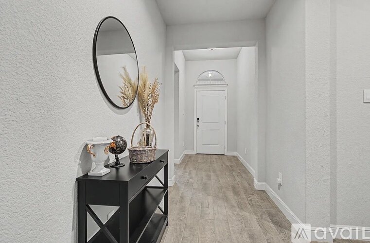 A hallway with a black console table and a round mirror on the wall.
