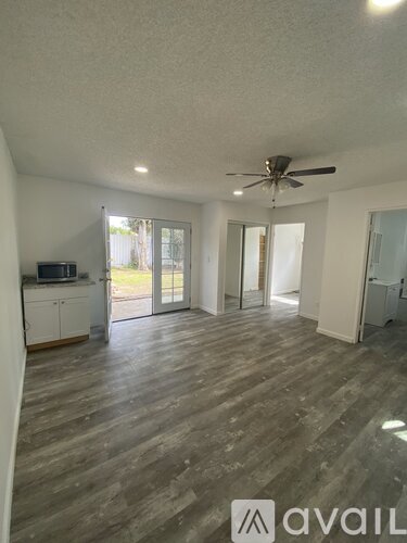 A spacious room with wooden flooring and a ceiling fan.