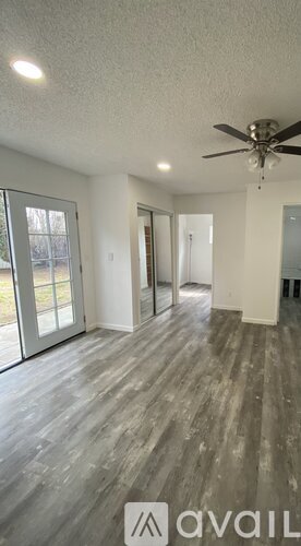 A room with a ceiling fan and sliding glass doors.