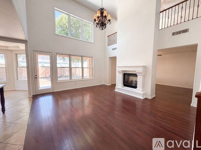 A large, empty living room with wood floors and a fireplace.
