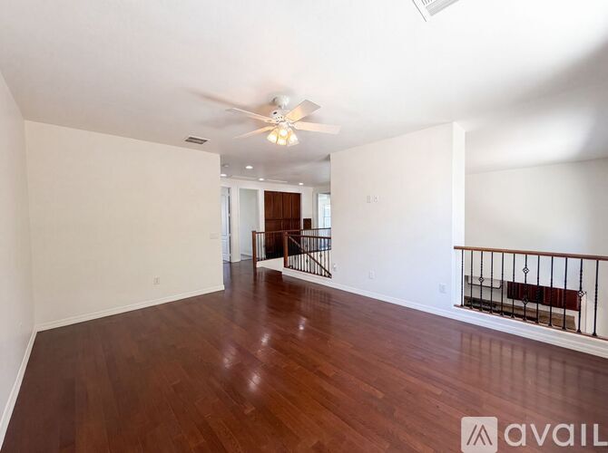 A spacious room with wooden floors and a ceiling fan.