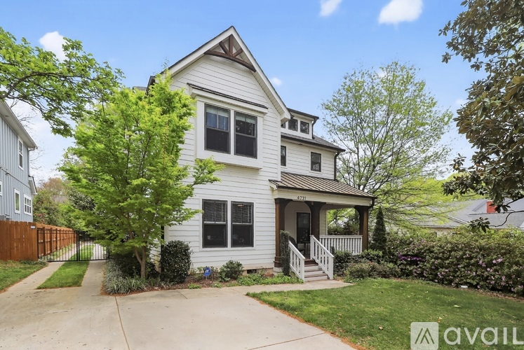 A two-story house with a front porch and a tree in the front yard.