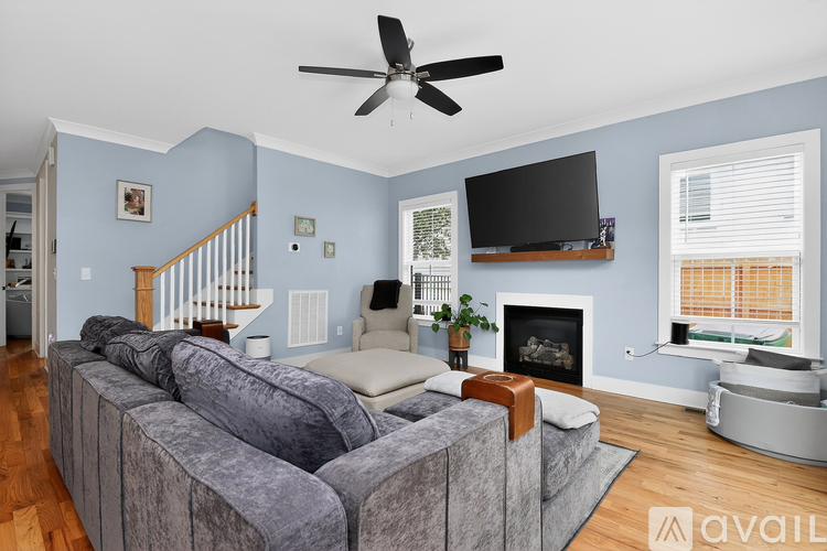 A living room with a grey couch and a fireplace.