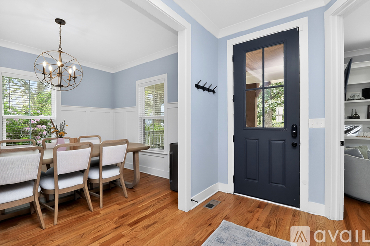 A dining room with a dark blue door and white chairs.