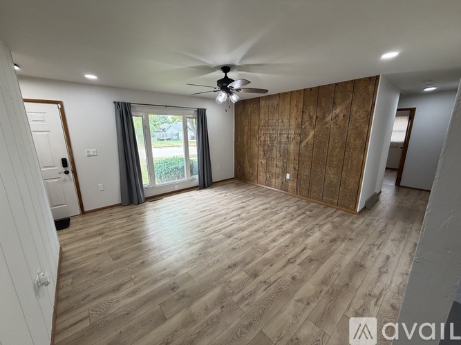 A spacious room with wooden flooring and a ceiling fan.