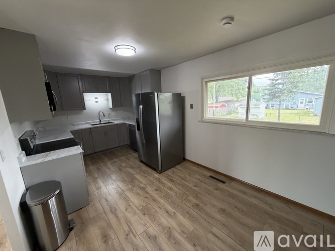 A kitchen with a refrigerator, sink, and cabinets.