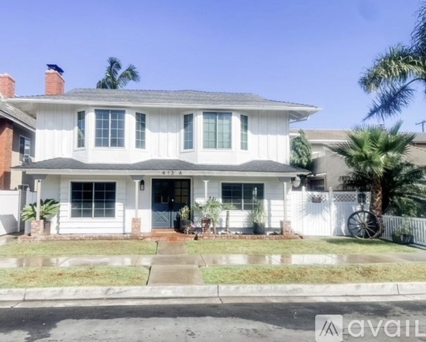 A white two-story house with a black roof and a porch.