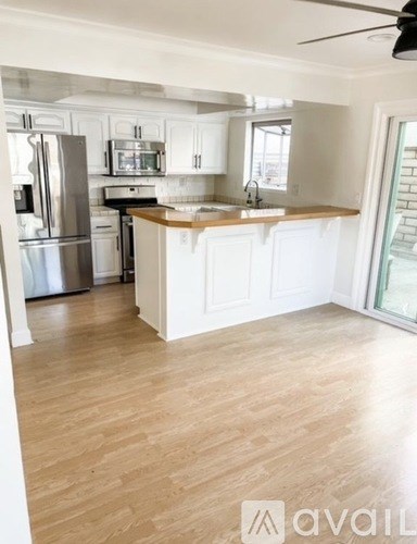 A kitchen with white cabinets and a wooden floor.