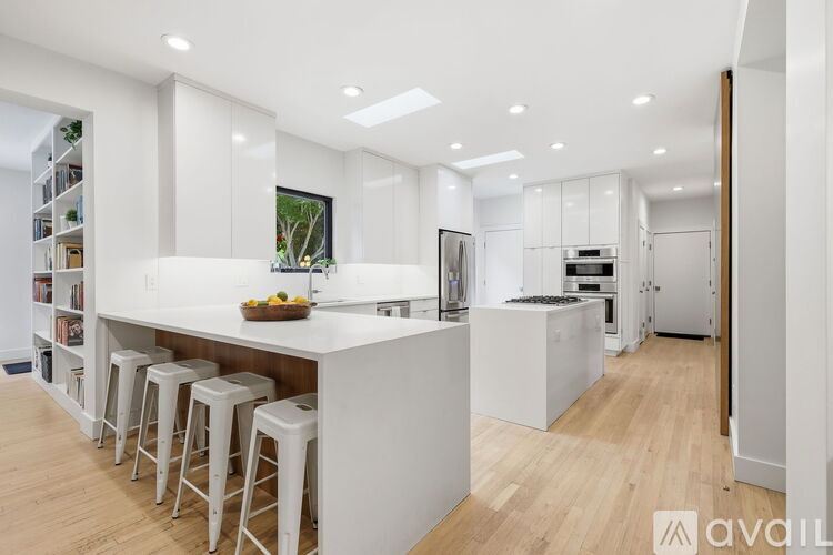 A modern kitchen with white cabinets and a wooden floor.