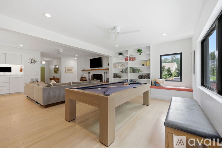 A well-lit room with a pool table and a couch.