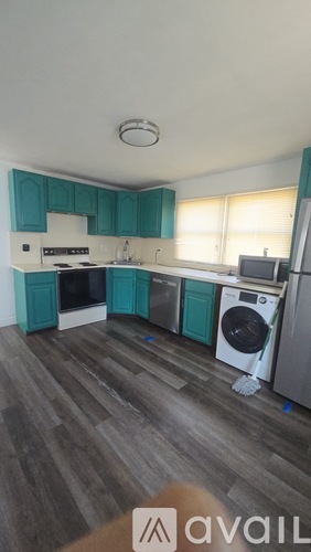 A kitchen with teal cabinets and a washing machine.