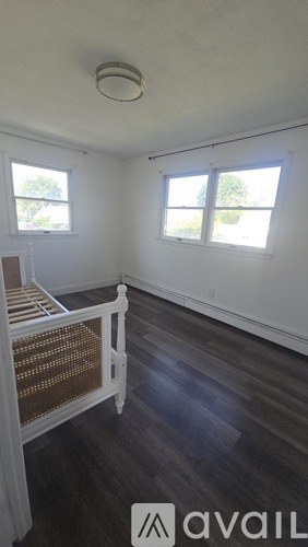 A room with a wooden floor and a window with a view of trees.