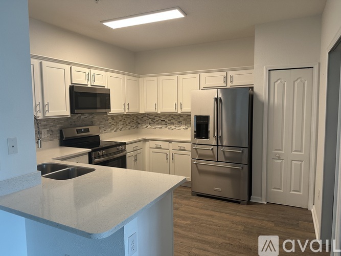 A kitchen with white cabinets and a stainless steel refrigerator.