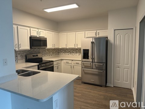 A kitchen with white cabinets and a stainless steel refrigerator.