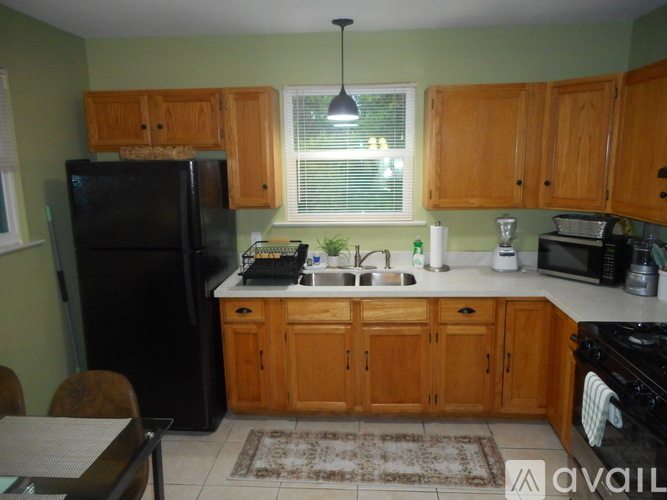 A kitchen with wooden cabinets and a black refrigerator.