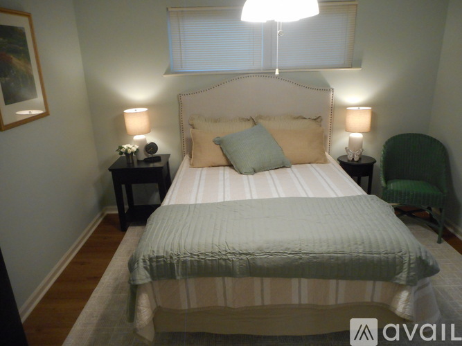 A bedroom with a bed, two lamps, and a chair.