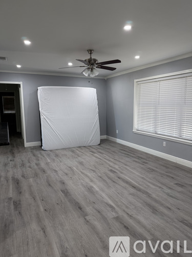A room with a ceiling fan and a large white object on the floor.
