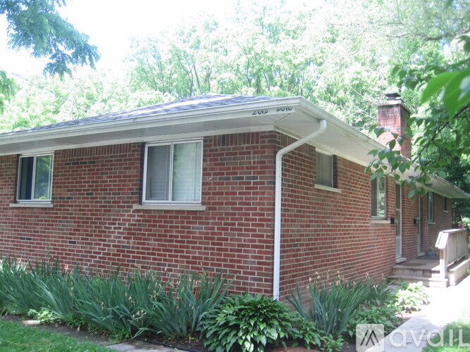 A red brick house with a white roof and a small porch.