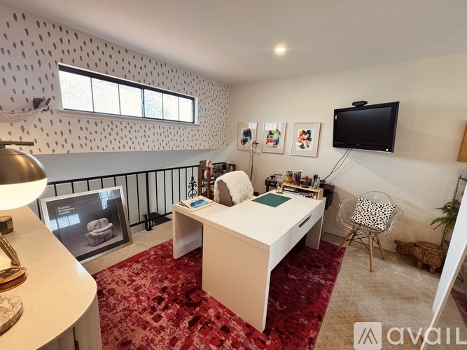 A room with a bed, desk, chair, and a television mounted on the wall.