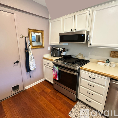 A kitchen with white cabinets and a wooden floor.