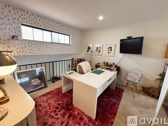A bedroom with a bed, desk, chair, and a television mounted on the wall.