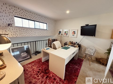 A bedroom with a bed, desk, chair, and a television mounted on the wall.
