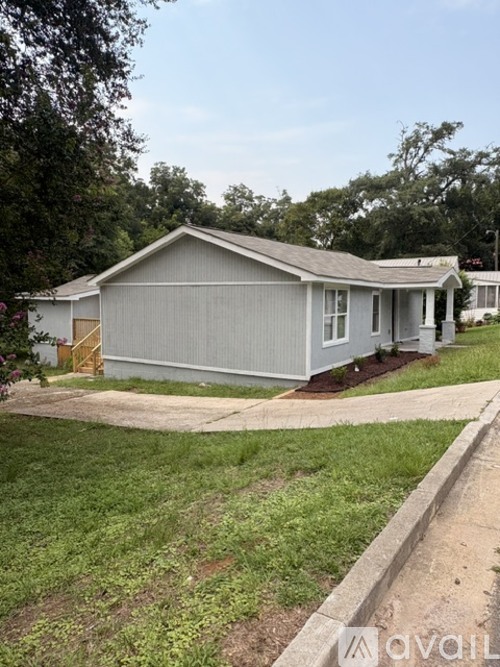A grey house with a brown door and a small porch.