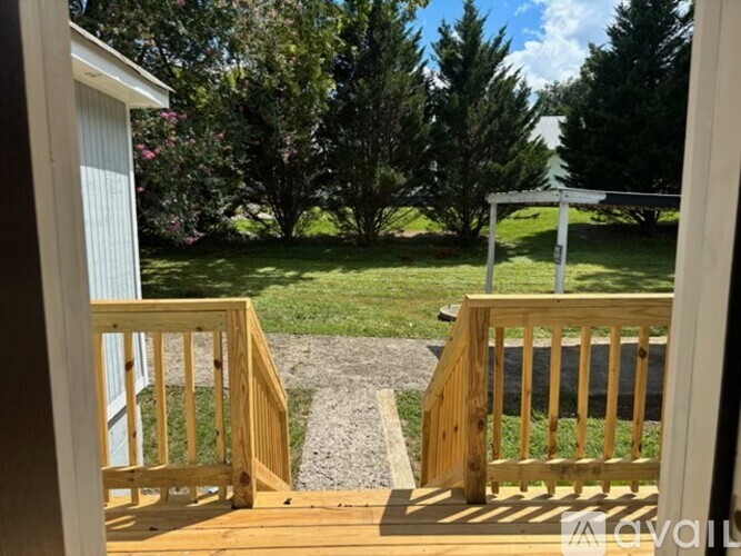 A wooden deck with a railing and steps leading to a grassy area.