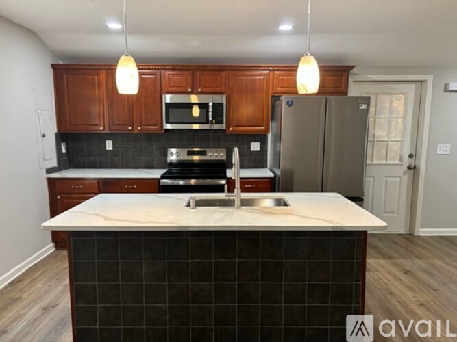 A kitchen with a black tile island and wooden cabinets.