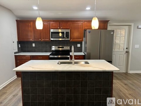 A kitchen with a black tile island and wooden cabinets.