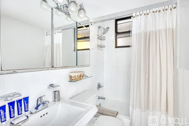 A white bathroom with a sink, mirror, and shower.