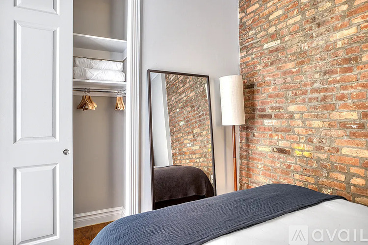 A bedroom with a brick wall and a bed with a blue blanket.