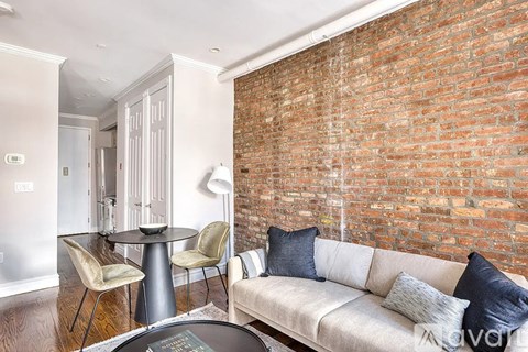 A living room with a white couch and a brick wall.