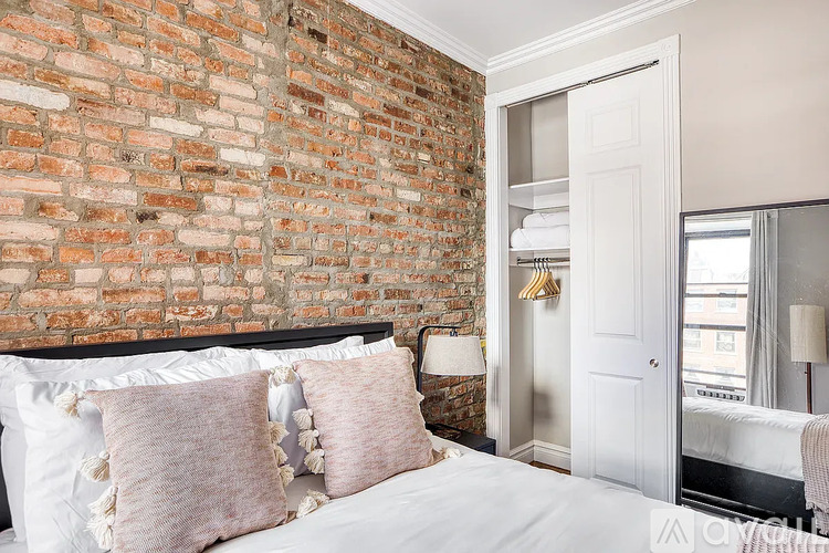 A bedroom with a brick wall and a white bed.