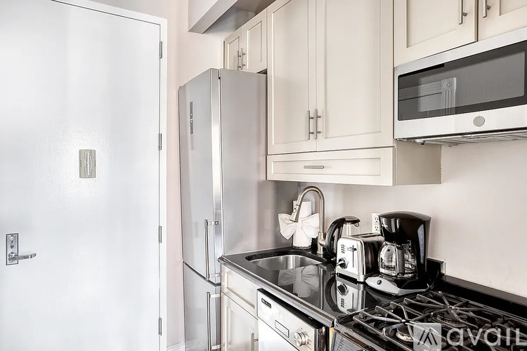 A kitchen with a stove, sink, and cabinets.