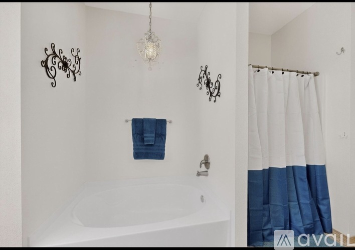 A white bathroom with a blue towel hanging on the wall.