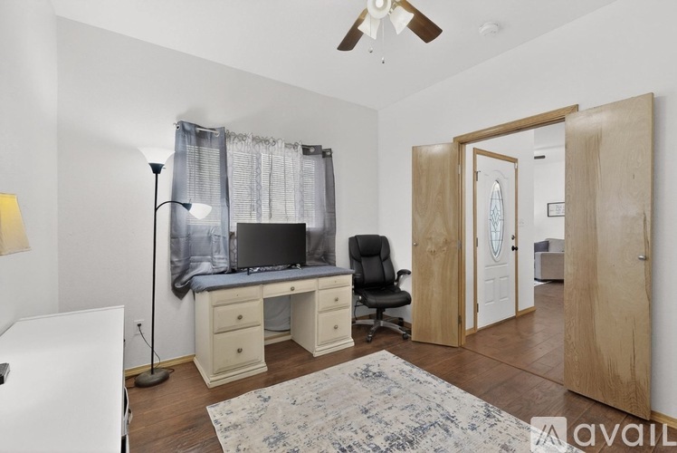 A room with a desk, chair, and a fan.