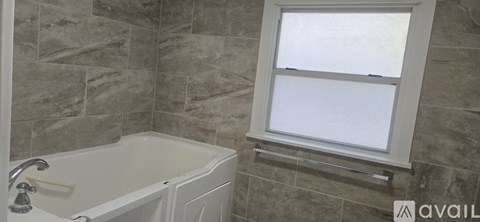 A bathroom with a tub and a window.