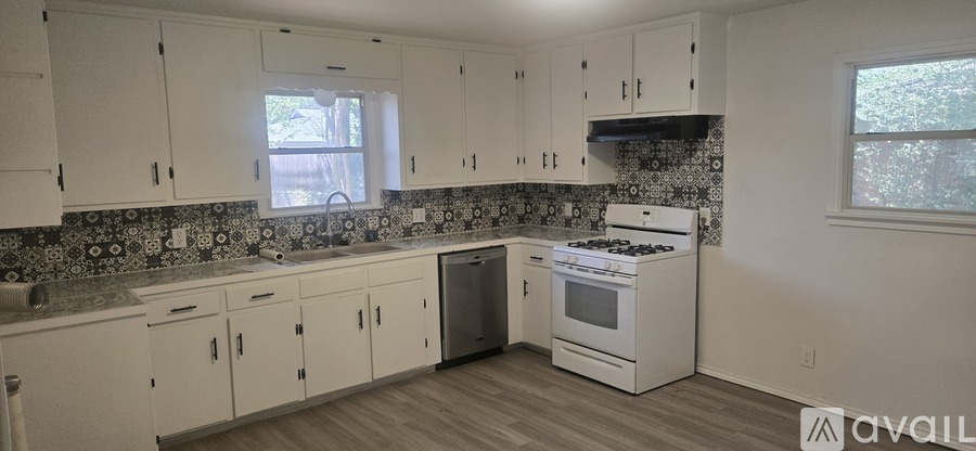 A kitchen with white cabinets and a tiled backsplash.