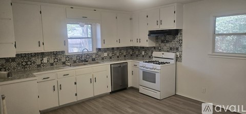 A kitchen with white cabinets and a tiled backsplash.