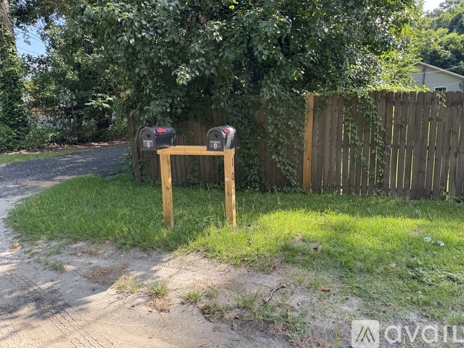 A wooden fence and mailboxes are in front of a house.