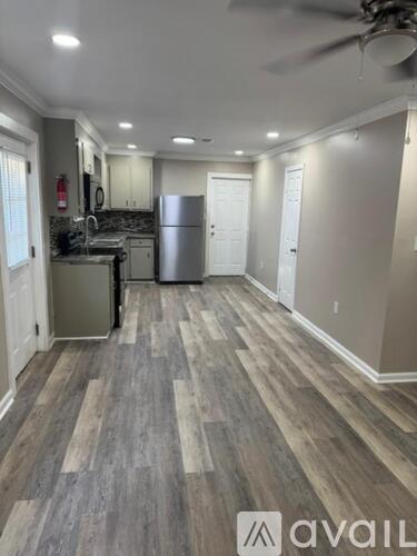 A kitchen with a refrigerator, sink, and cabinets.