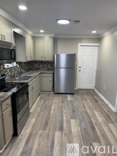 A kitchen with a refrigerator, stove, and cabinets.
