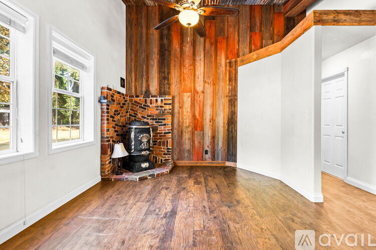 A room with a wood burning stove and a wooden wall.