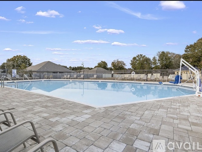 A large outdoor swimming pool surrounded by a fence and trees.
