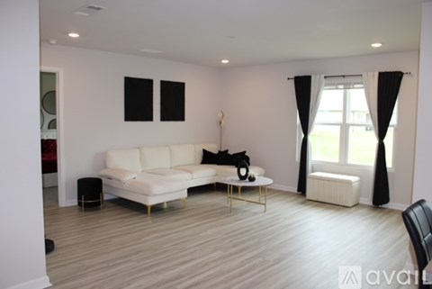 A living room with a white couch and a black dog.