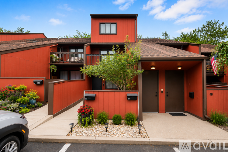 A modern house with a red exterior and a grey car parked in front.